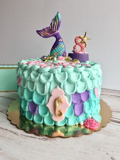 there is a cake decorated with mermaid decorations on the top and under it's tail