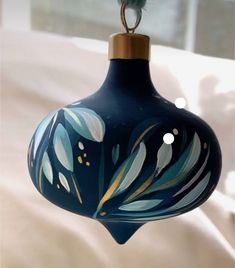 a blue glass ornament hanging from a string on a bed with white sheets