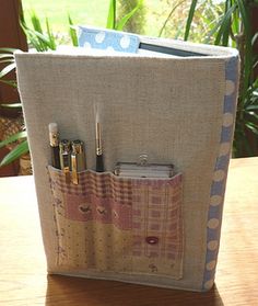 a bag with some pens and pencils in it sitting on a table next to a window