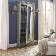 a bedroom with blue walls and furniture in the corner, including a large armoire