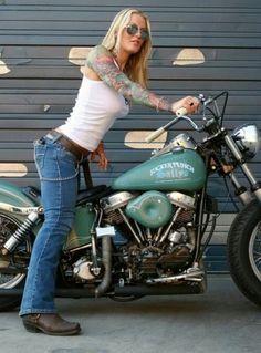 a woman sitting on top of a motorcycle in front of a garage door wearing sunglasses