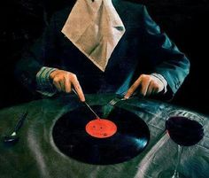 a man sitting at a table with a record in front of him, holding a knife and fork