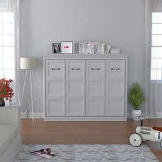 a living room filled with white furniture and lots of plants on top of the table