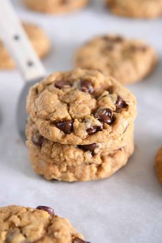 chocolate chip cookies are stacked on top of each other with a spatula in the background