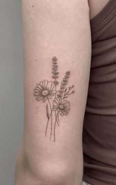 a woman with a tattoo on her arm has flowers in the middle of her arm