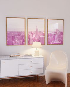 two framed pictures hang on the wall above a white dresser and chair in a room with hardwood floors