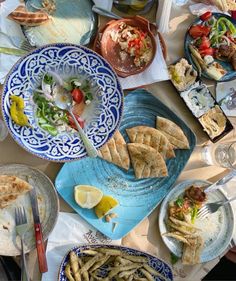 a table full of plates and bowls with food on them including crackers, salad