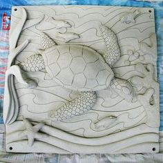 an intricately carved sea turtle and fish design on a white marble slab with blue background