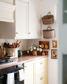 a kitchen with white cabinets and wooden counter tops, baskets hanging on the wall above the stove