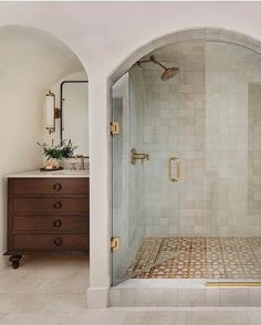 a bathroom with a walk in shower sitting next to a sink and a mirror on the wall