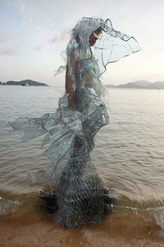 a woman is standing in the water with her dress flowing over her head and body