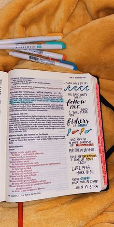 an open bible with writing on it and three pencils laying next to the book