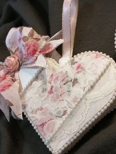 an ornament shaped like a heart with flowers on it and ribbon attached to the front