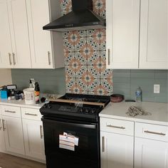 a stove top oven sitting inside of a kitchen next to white cabinets and cupboards