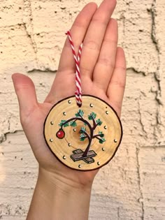 a hand holding a wooden ornament with an apple tree on it and a candy cane