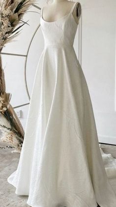 a white wedding dress on display in front of a wreath