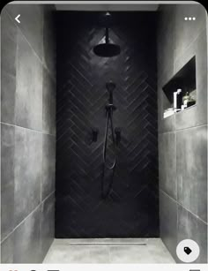 a bathroom with a black tiled wall and shower head