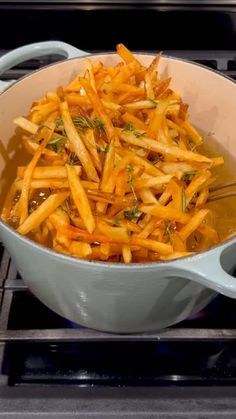 french fries are being cooked in a pot on the stove