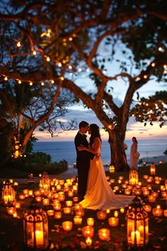 a bride and groom standing in front of many lit candles at night with the ocean in the background