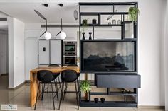 a dining room table with chairs and a television on it's stand next to a kitchen