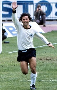 a soccer player is running towards the ball in front of his team mates and fans