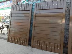 two wooden doors with rivets on the side of a building in front of a brick wall