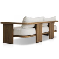 a wooden bench with white pillows on it's back and seat cushioned to the side