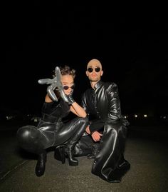 a man and woman dressed up in black leathers pose for a photo at night