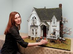 a woman is holding up a model house