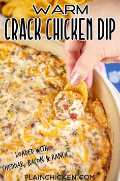 a hand dipping a tortilla chip into a cheesy dip in a casserole dish