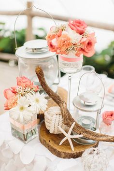 a table topped with vases filled with flowers and deer antlers on top of a wooden