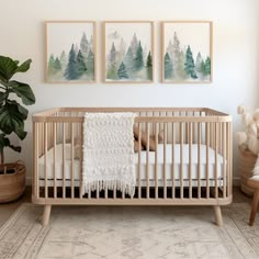 a baby's crib with two paintings on the wall