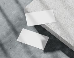 two blank white business cards sitting on concrete