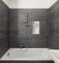 a white bath tub sitting under a window next to a shower head and faucet