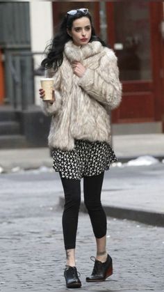 a woman walking down the street while holding a cup