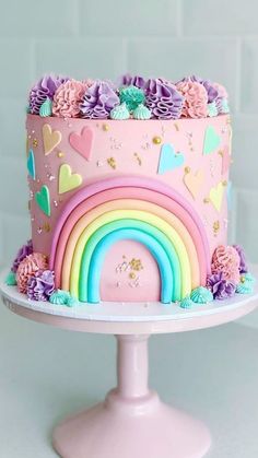 there is a pink cake with rainbows and flowers on it