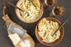 two bowls of pasta with parmesan cheese on the side