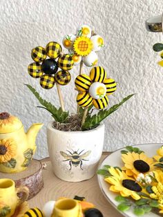 a table topped with yellow and black flowers next to teapots filled with fake sunflowers