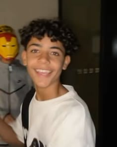 a young boy standing next to an iron man mask