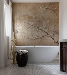 a white bath tub sitting in a bathroom next to a wall with a painting on it