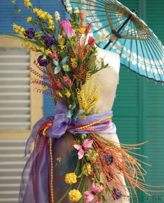 a mannequin is adorned with flowers and an umbrella