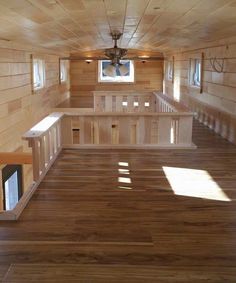 the inside of a tiny house with wood floors and windows on each side of the room