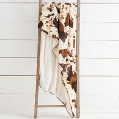 a towel is hanging on an old ladder next to a white wall and wooden planks