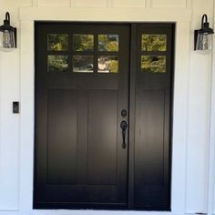 the front door is painted black and has two lights on each side, along with an outside light