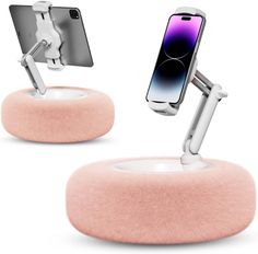 two cell phones are connected to an air vent on top of a pink stand with a phone in it