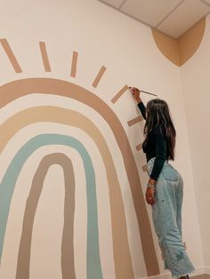 a woman is painting a rainbow mural on the wall