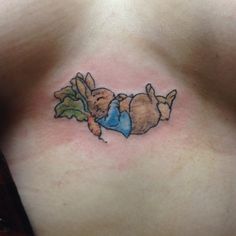 a small tattoo on the back of a woman's chest, depicting two rabbits eating lettuce