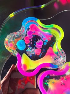 a person is holding a colorful object in front of a glass plate with bubbles and stars on it