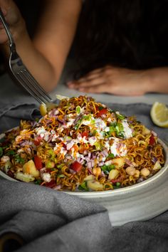 a plate of food on a table with a fork in it and someone holding their hand over the bowl