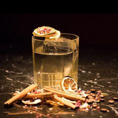 a glass filled with liquid next to some cinnamons and other things on the table